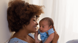 An African American woman holding an infant close to her. 