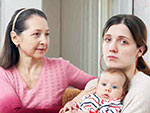 Photo of a grandmother comforting a stressed mother holding her baby